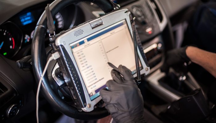 Automobile computer diagnosis. Car mechanic repairer looks for engine failure Automobile computer diagnosis. Car mechanic repairer looks for engine failure on diagnostics equipment in vehicle service workshop